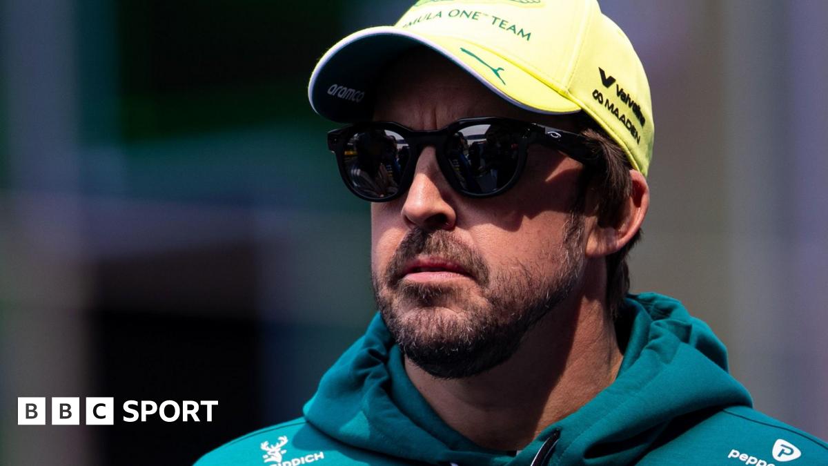 Fernando Alonso wearing sunglasses, an Aston Martin hoodie and a yellow cap