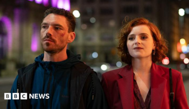 Left to right: Diana Williams (Hannah Onslo), Michael Kavanagh (James Nelson-Joyce), Ronnie Phelan (Sean Bean), Jamie Phelan (Jack McMullen), Elaine Phelan (Julie Graham). They are all seated ina royal blue velvet booth except for Sean Bean who is standing in the centre. The Liver Building can be seen in the background out of the window.