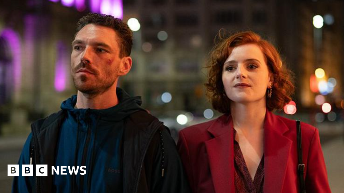Left to right: Diana Williams (Hannah Onslo), Michael Kavanagh (James Nelson-Joyce), Ronnie Phelan (Sean Bean), Jamie Phelan (Jack McMullen), Elaine Phelan (Julie Graham). They are all seated ina royal blue velvet booth except for Sean Bean who is standing in the centre. The Liver Building can be seen in the background out of the window.