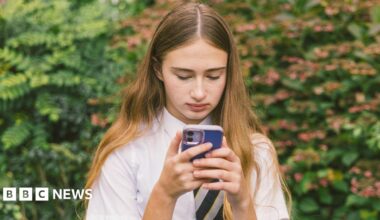 A teenage girl in school uniform stares at a phone