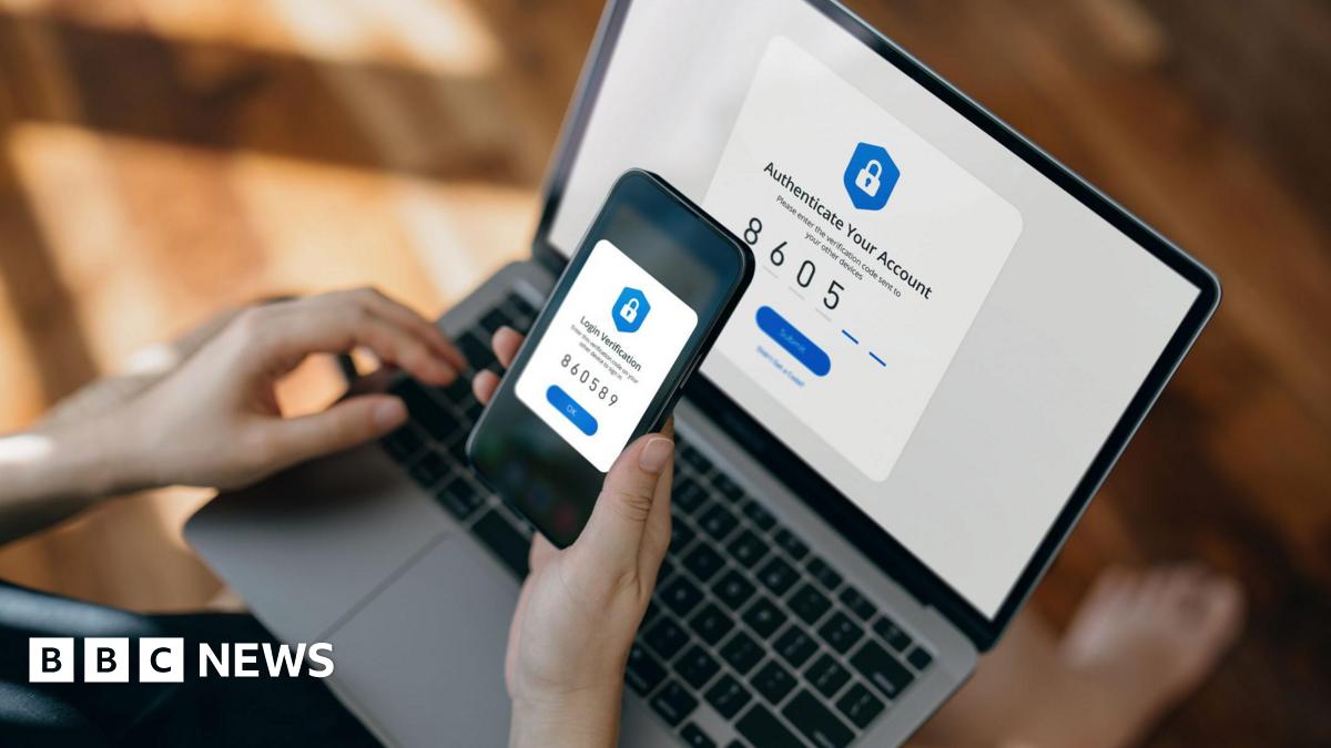 A person holds a smartphone over a laptop to complete a two-factor authentication process. Both screens display security prompts and matching verification codes.