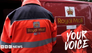 An employee of Royal Mail sorts parcels and letters in the back of his delivery van. The Royal Mail branding is on the back of his jacket and on the side of the van.