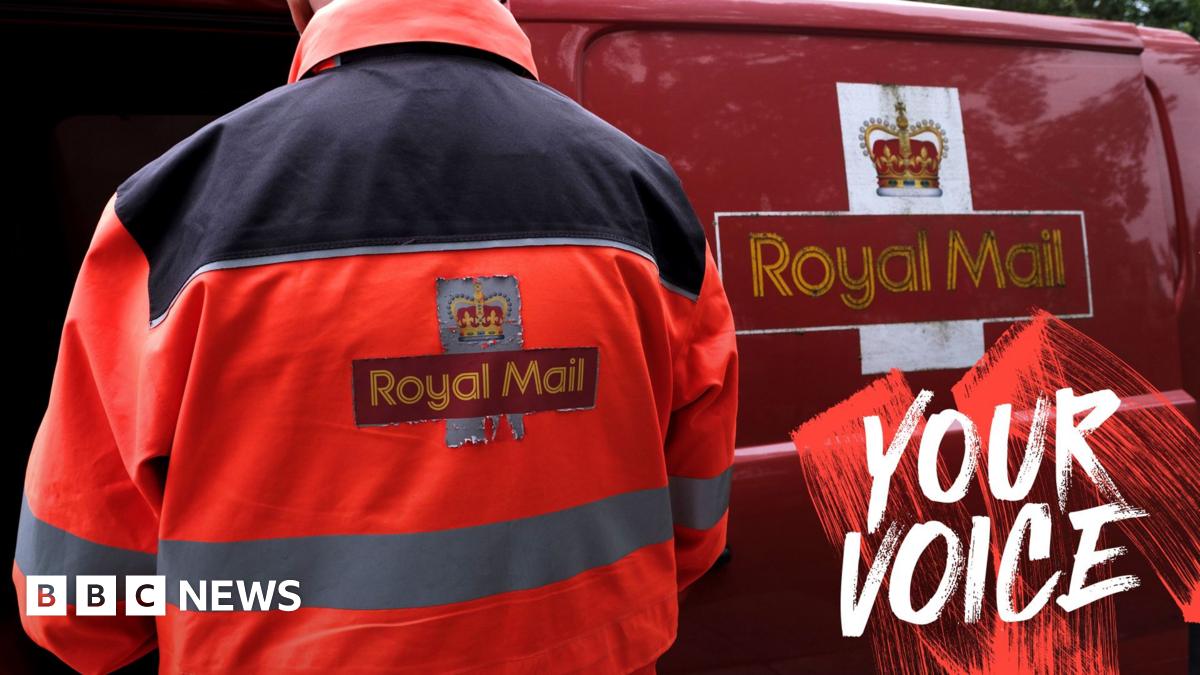 An employee of Royal Mail sorts parcels and letters in the back of his delivery van. The Royal Mail branding is on the back of his jacket and on the side of the van.