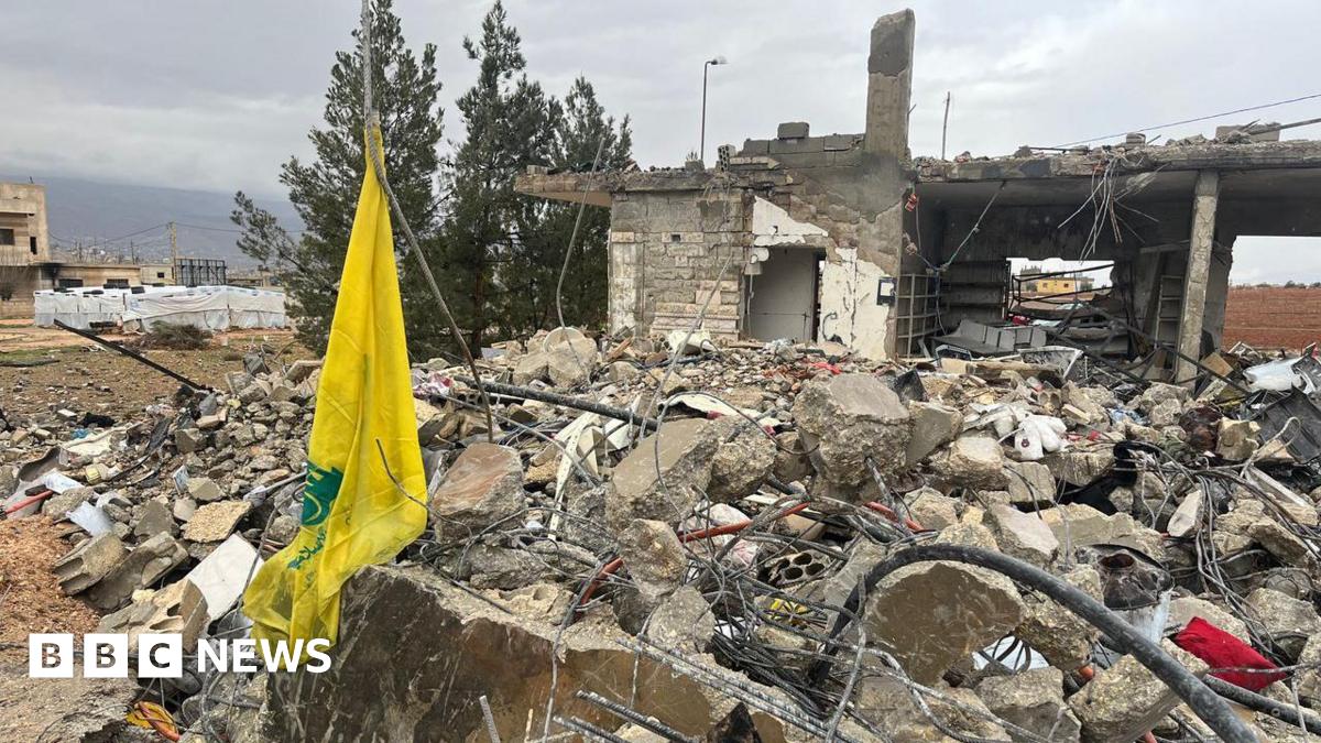 The yellow flag of the Hezbollah group hanging by the ruins of a house