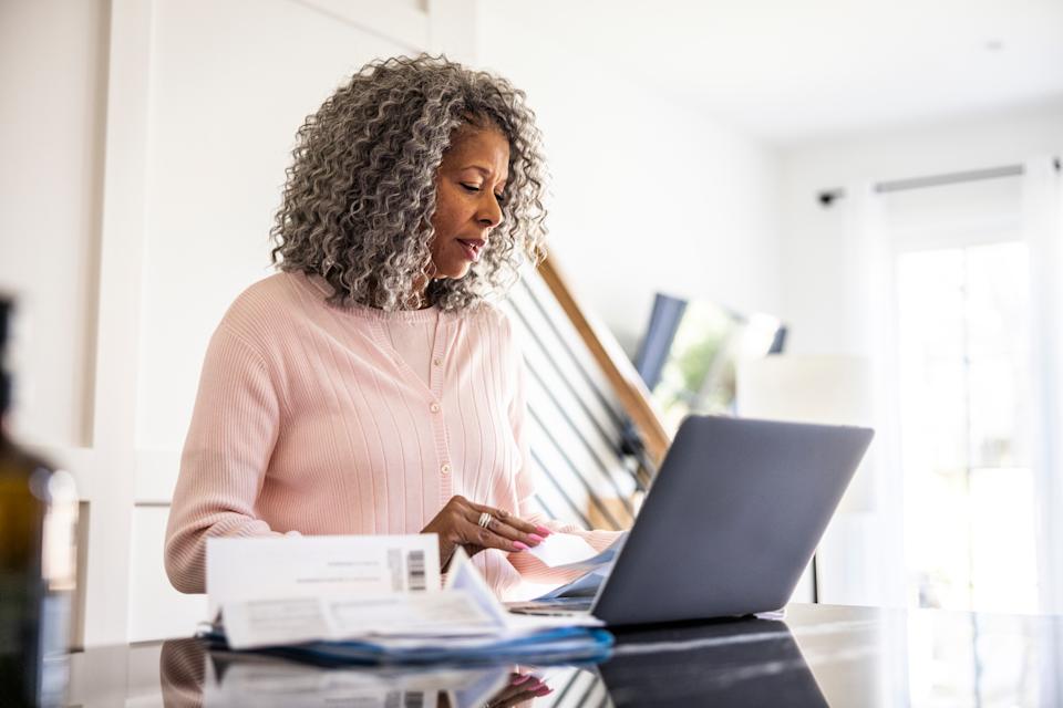 Senior woman using laptop and paying bills at home