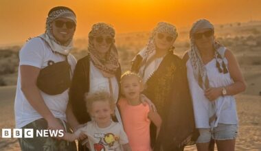 A photo of Hollie and her family dressed in holiday clothing. They are stood in a desert and there is an orange sunset behind them.