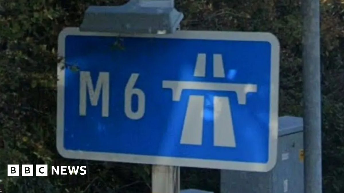A blue M6 sign surrounded by bushes.