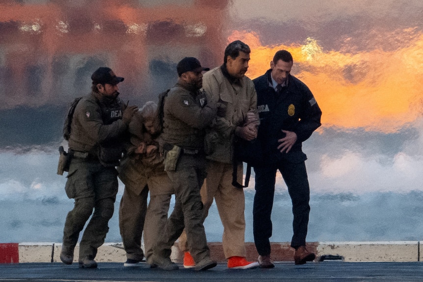 A man in handcuffs flanked by police officers