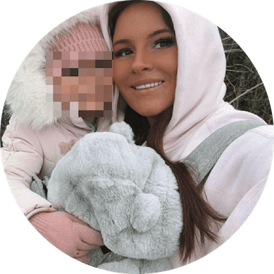 A woman dressed in pink holding a young child in a parka
