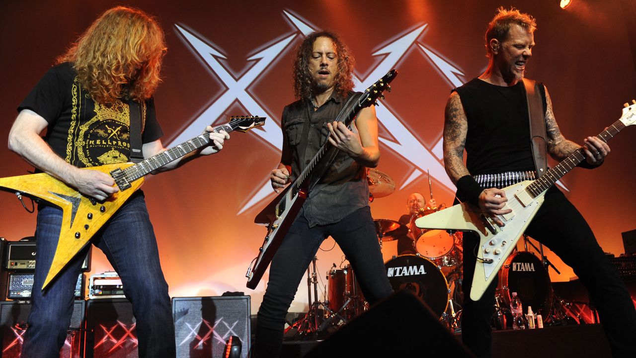 James Hetfield and Kirk Hammett of Metallica playing guitar onstage with Dave Mustaine of Megadeth