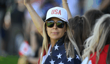Brandt Snedeker's wife Mandy looks on through sunglasses at the 2024 Presidents Cup while wearing a Team USA cap and with a a US flag wrapped around her