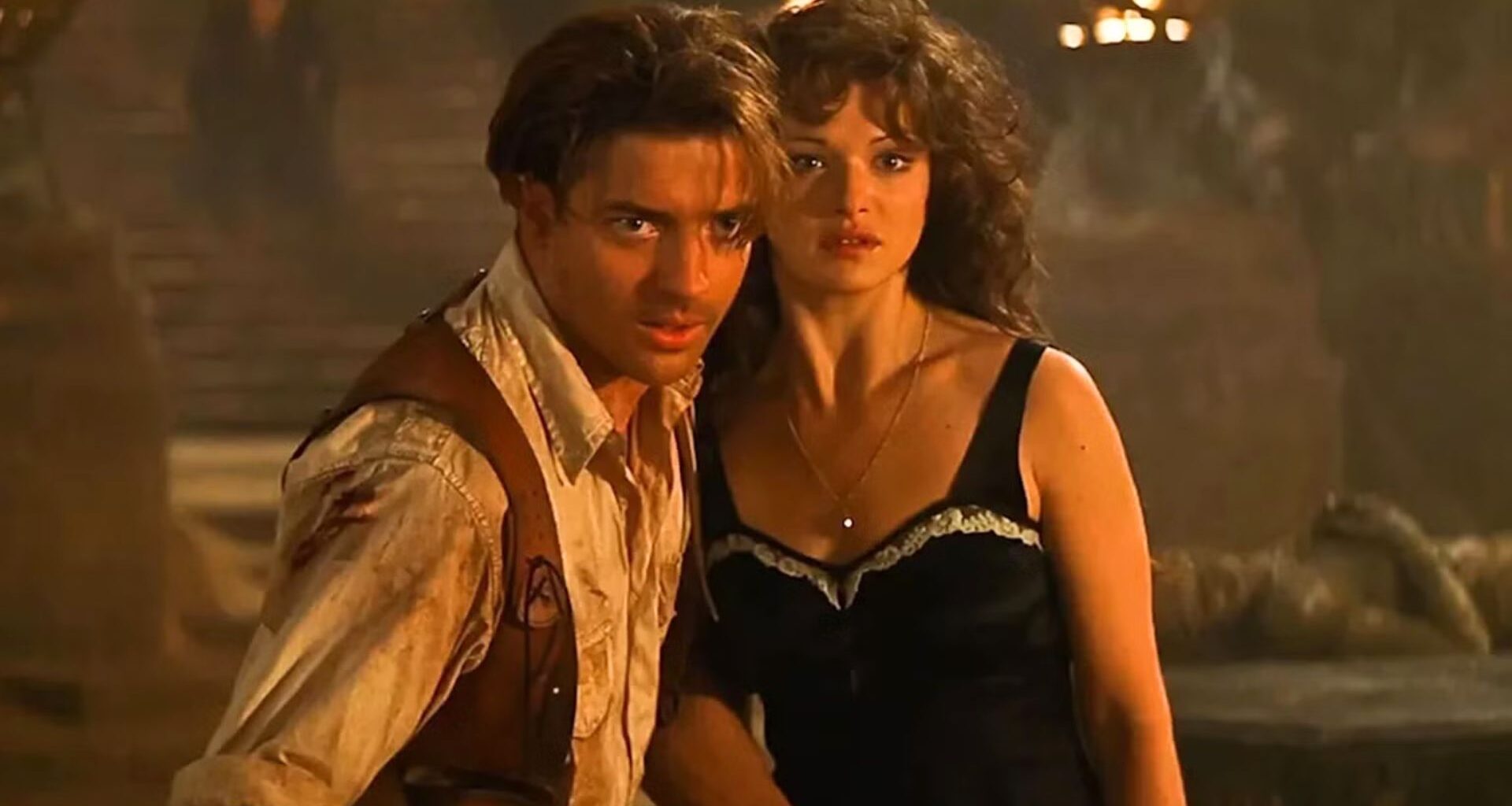 Brendan Fraser lunges for something while Rachel Weisz stays back