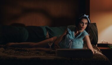 Kaia Gerber as Mitzi, reclining on a sofa, in Palm Royale season 2.