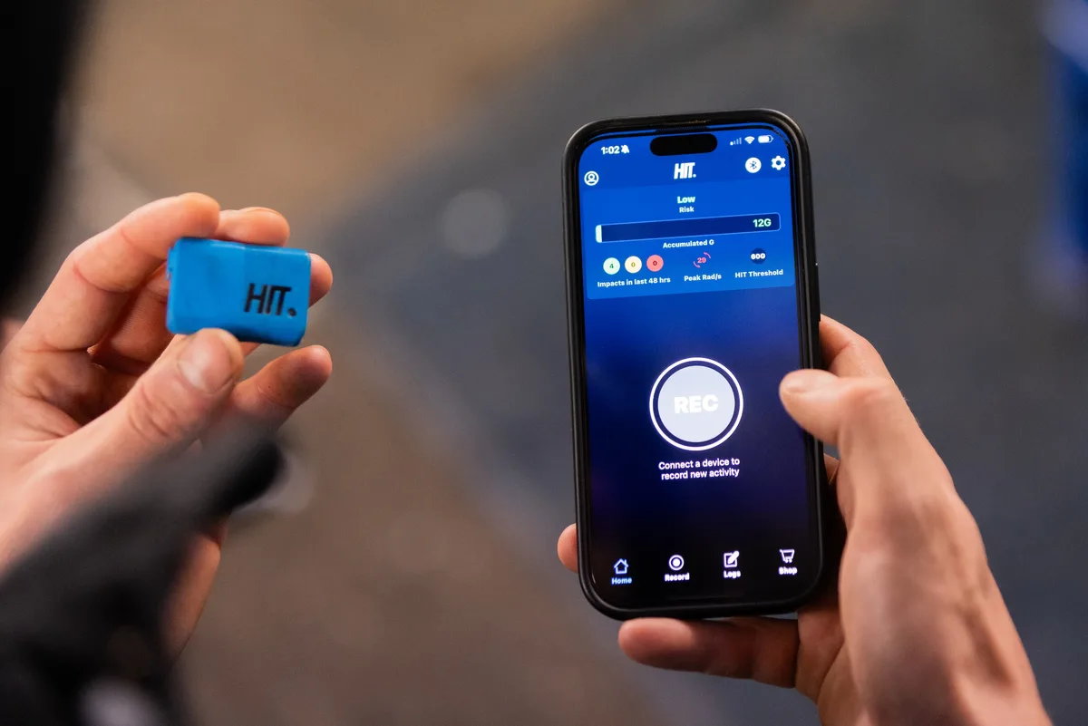 Rider holding HIT sensor next to smartphone displaying connection screen in the HIT app