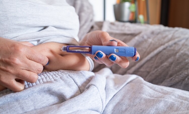 Close up of seated woman injecting weight loss drug GLP-1 into abdomen