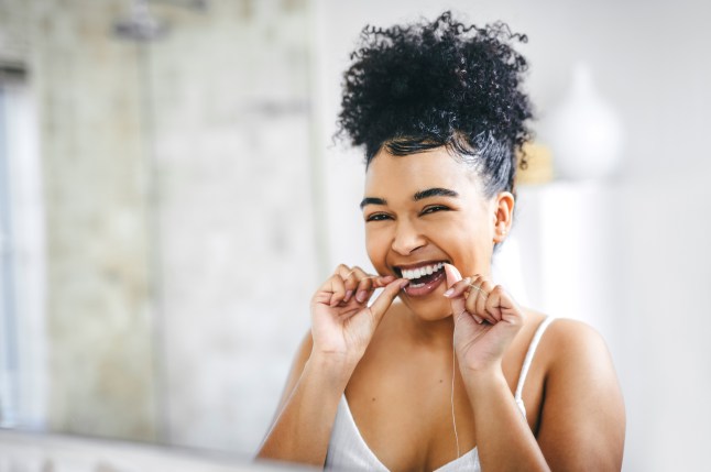 Shot of a beautiful young woman flossing her teeth