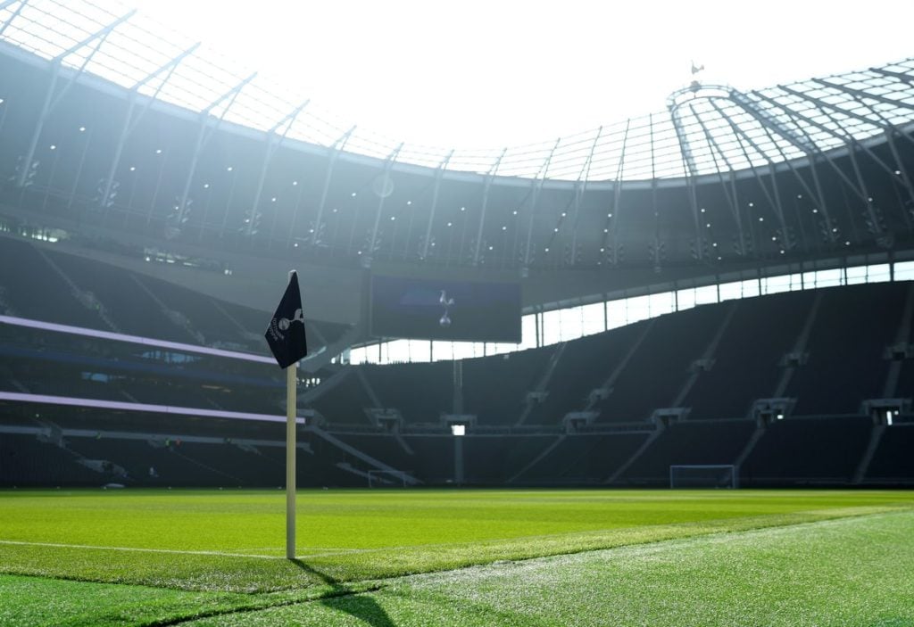 A low-angle shot of the Tottenham Hotspur Stadium, taken from behind the corner flag.