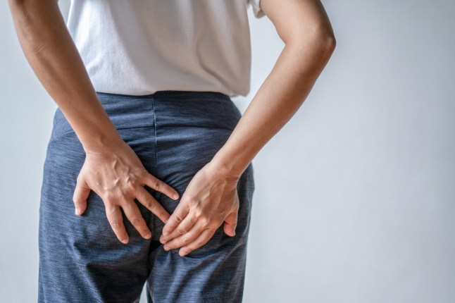 Woman with hemorrhoids holding her ass in pain.
