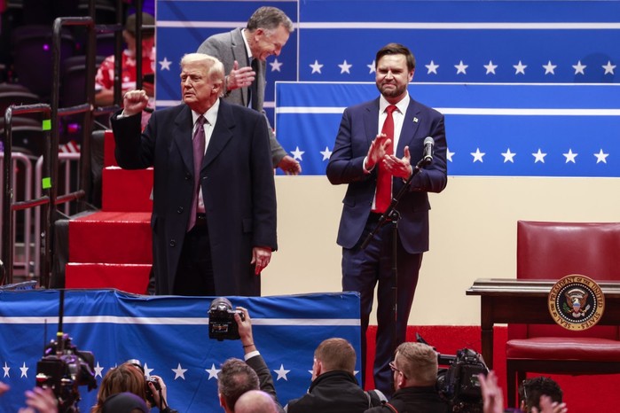 Donald Trump raises his fist on a stage during the 2025 presidential inauguration.