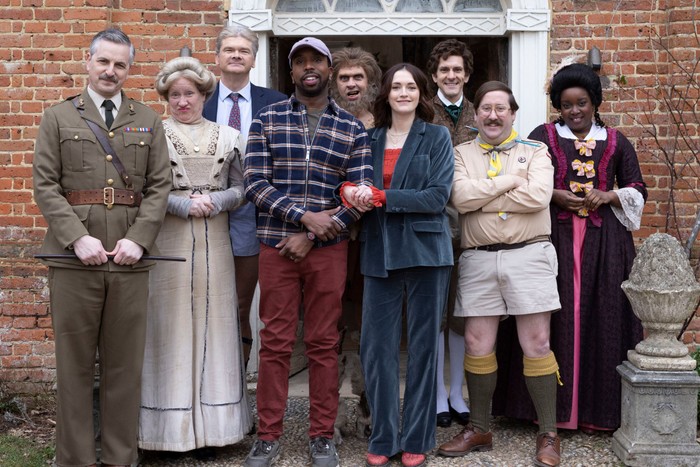 The cast of Ghosts looking into camera standing outside Button House
