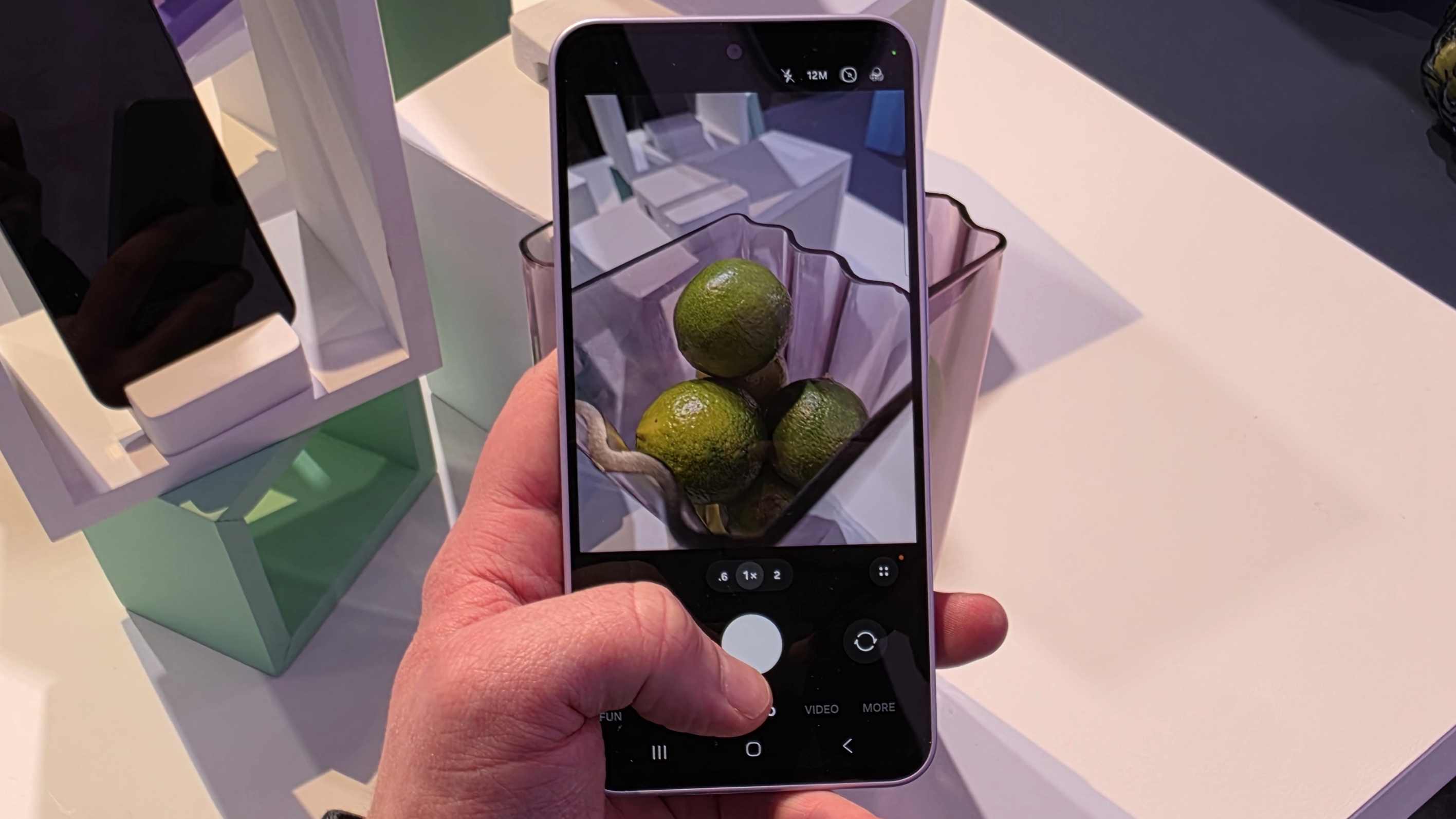 The Samsung Galaxy A37 in a man's hands, in the camera app, showing a bowl of limes.