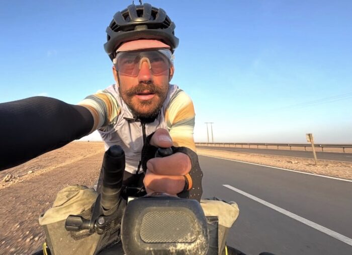 Swiss cyclist Adrien Liechti pedalling on a road in the Western Sahara.