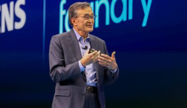 Man speaking on stage with Siemens and foundry visible in the background.