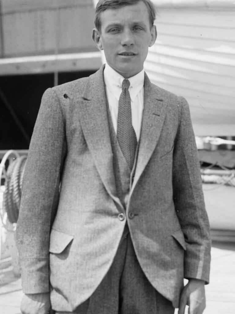 Black-and-white portrait of Welsh flyweight boxer Jimmy Wilde standing on the deck of a ship wearing a suit and tie, circa 1920.