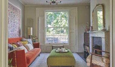 Living room with bay window, marble fireplace, orange sofa, tapestry and green ottoman
