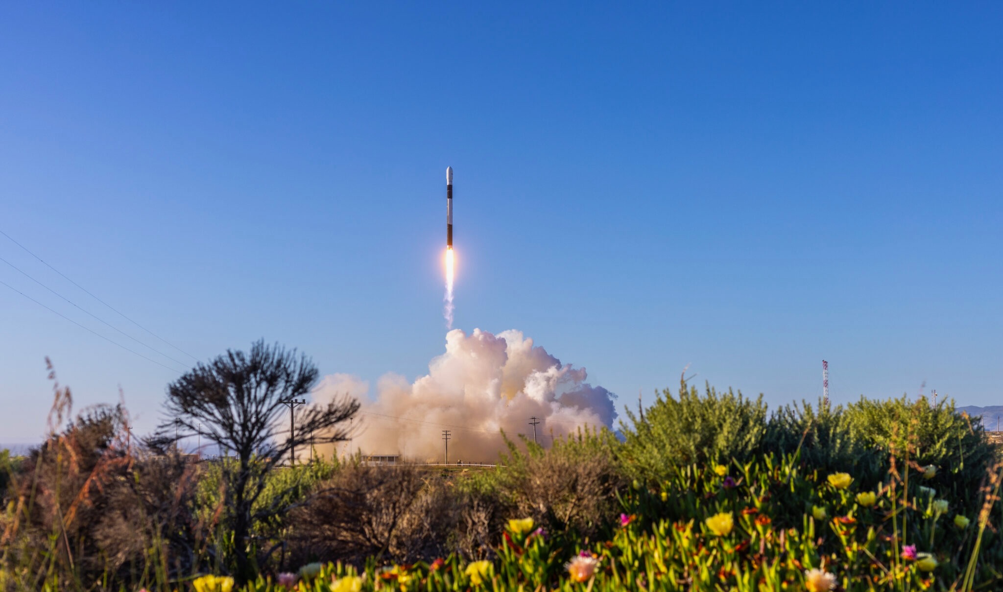 a black and white rocket launches into a blue sky