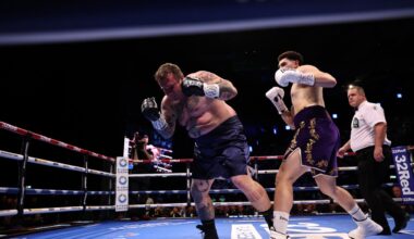 Boxer landing a right hand on a heavier opponent during a heavyweight fight inside a boxing ring.
