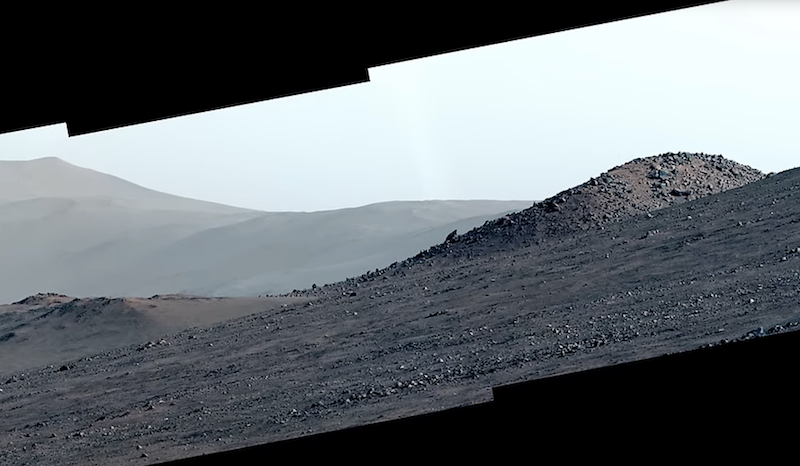 Rubies on Mars: View of hilly, barren gravel-covered terrain with mountains in the distance.