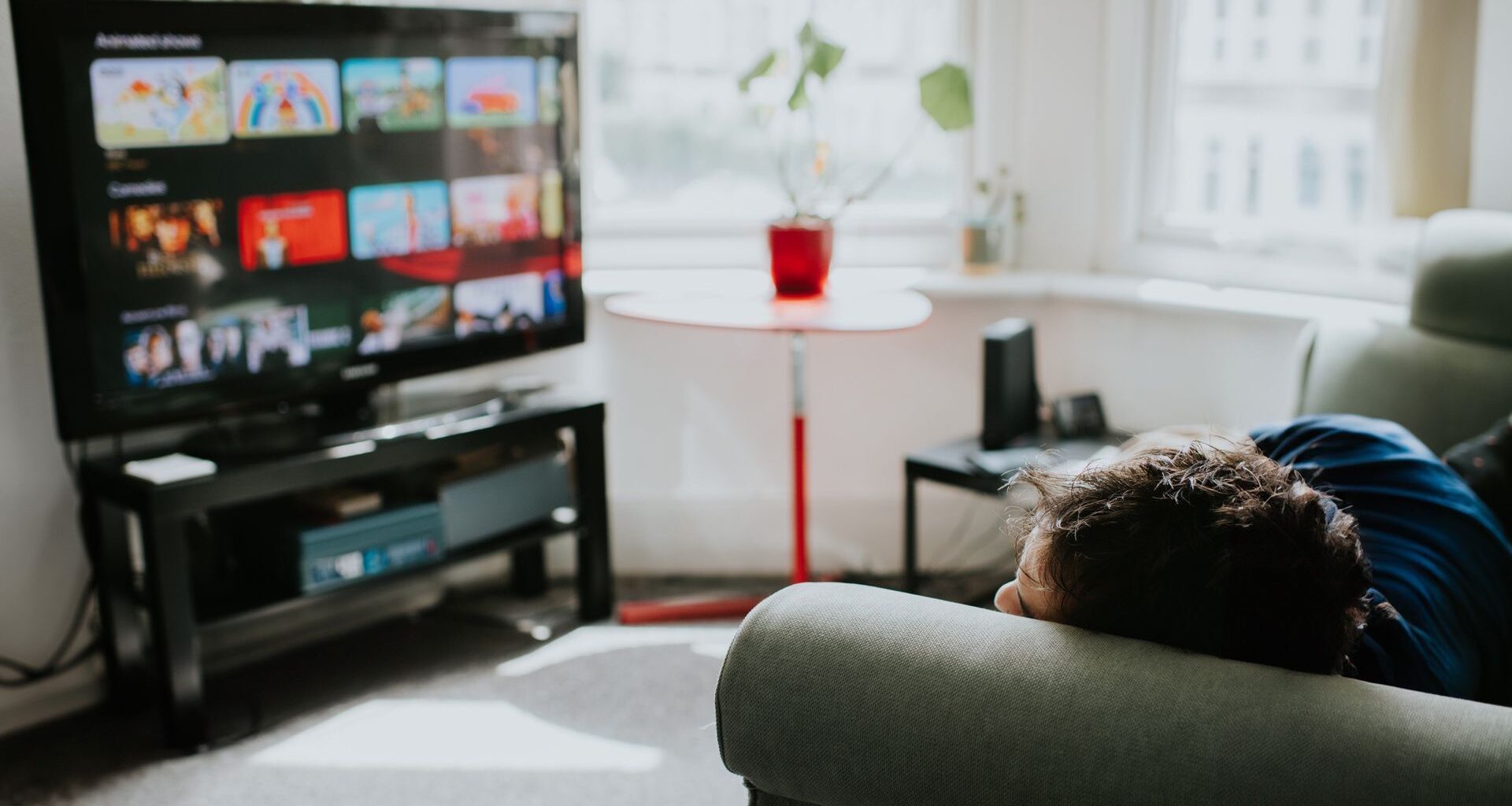 A person relaxes on a comfortable couch choosing a programme on a streaming service.