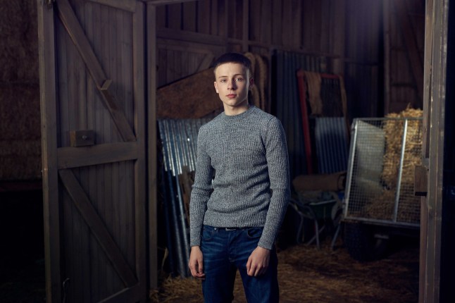 Sam Hall posing as his Emmerdale character Samson Dingle in a barn.