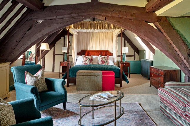A suite in Ellenborough Park with four-poster bed, a seating area, and wooden beams on the ceilings.