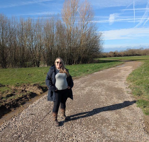 Mel Evans smiling in a rain jacket and wellies and sunglasses on a dirt track in the grounds of Ellenborough Park