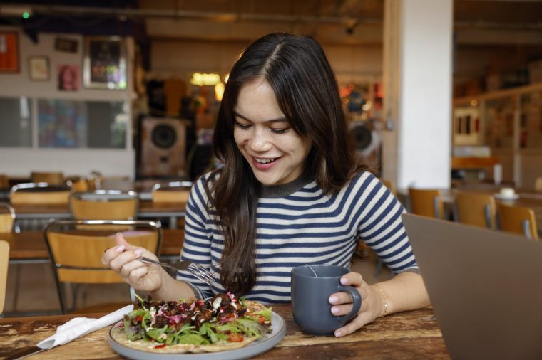 A woman eats vegetarian food in a cafe