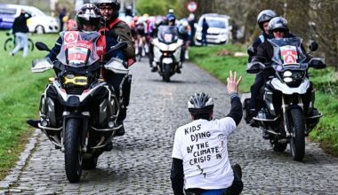 A protestor sits on the road while riders compete in the 'Ronde van Brugge' men's elite one-day cycling race, 202,9 km from and to Bruges on March 25, 2026. (Photo by MAARTEN STRAETEMANS / Belga / AFP) / Belgium OUT