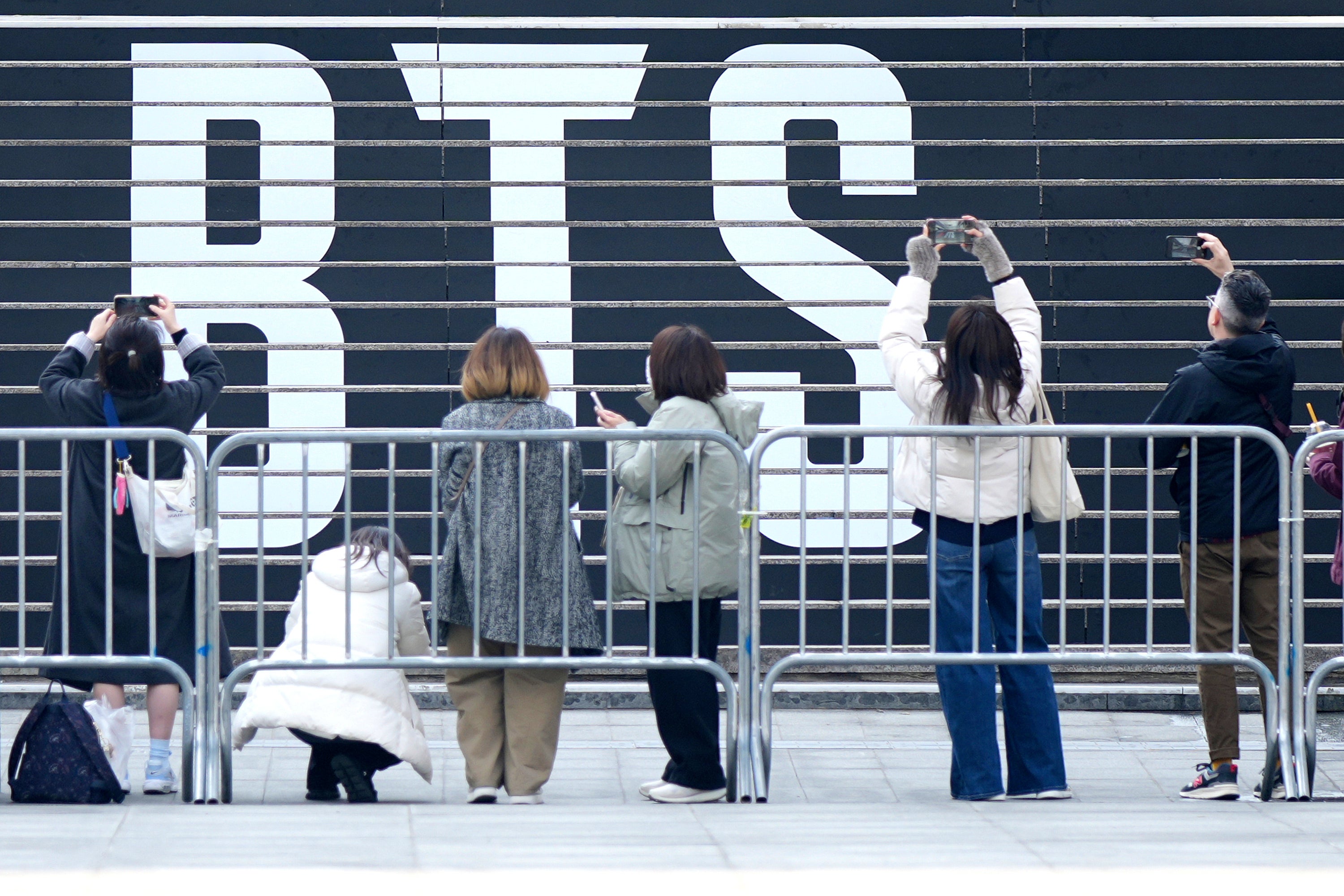 Fan of K-pop band BTS in front of a logo of BTS in Seoul, South Korea, Monday, March 16, 2026. (AP Photo/Lee Jin-man)