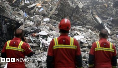 A woman in Tehran, Iran, stands in a bombed building looking out over piles of debris. Photo: 21 March 2026.
