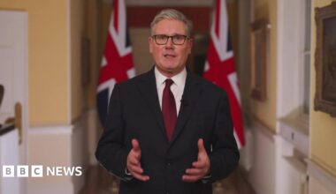 Catherine wearing burgundy carrying yellow daffodils and Welsh flags as people take pictures in the background