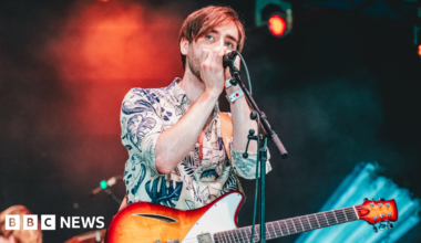Isaac Neilson performing on stage with a guitar and microphone at Y Not festival in Pikehall in Derbyshire