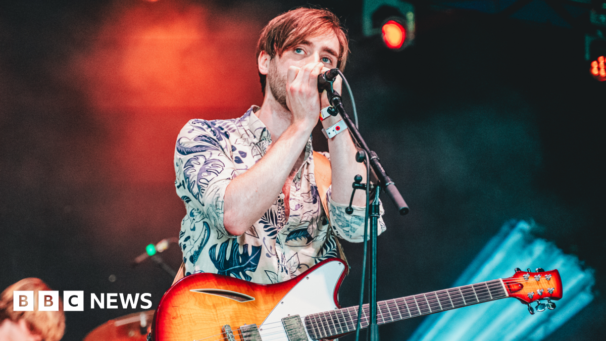 Isaac Neilson performing on stage with a guitar and microphone at Y Not festival in Pikehall in Derbyshire