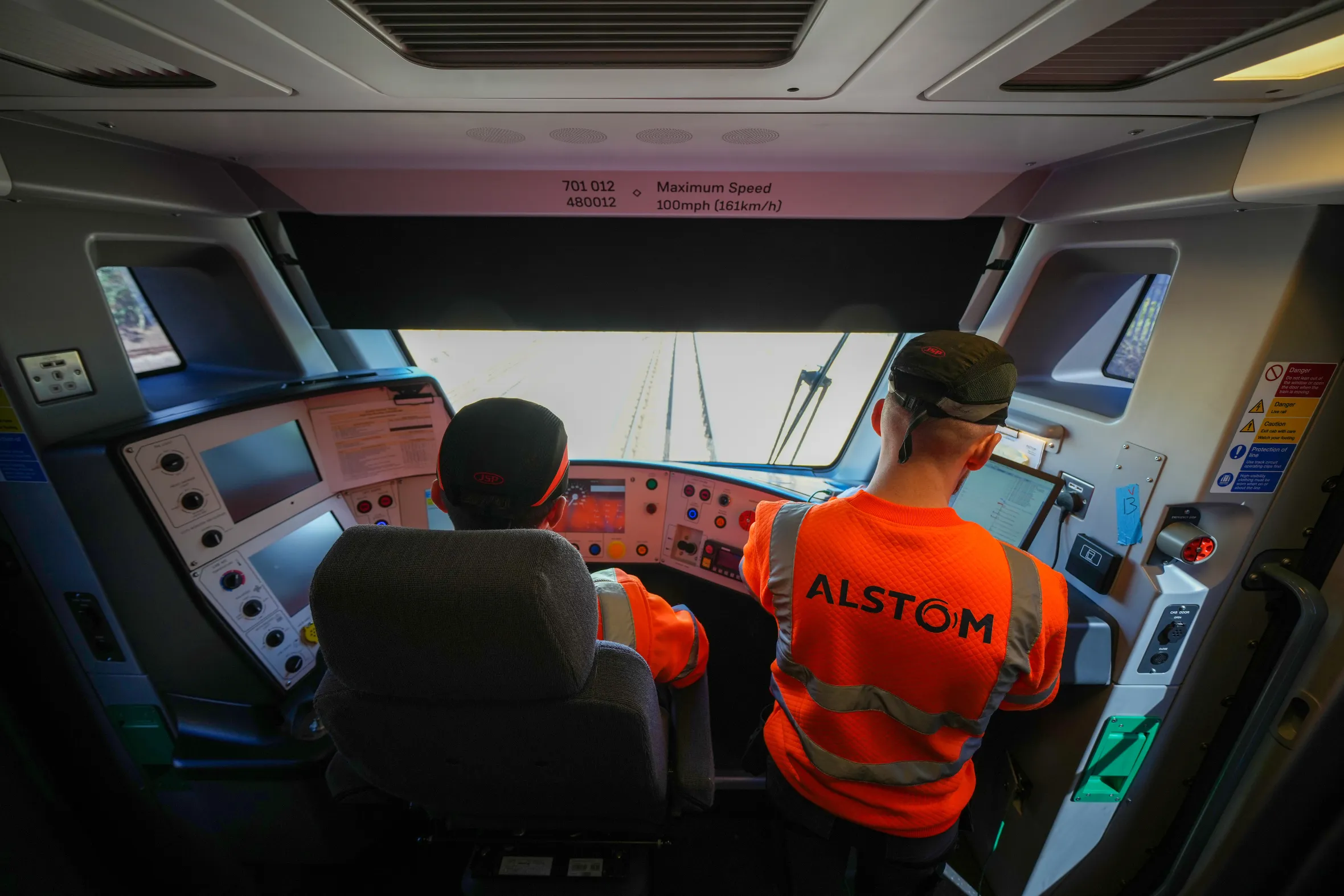 Engineers inside the cab of an Alstom train at a manufacturing testing facility.