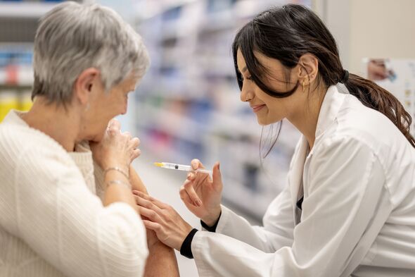 Asian Nurse Administers Injection to Elderly White Woman Patient in Clinic Setting Asian Nurse Administers Injection to Elderly White Woman Patient in Clinic Setting