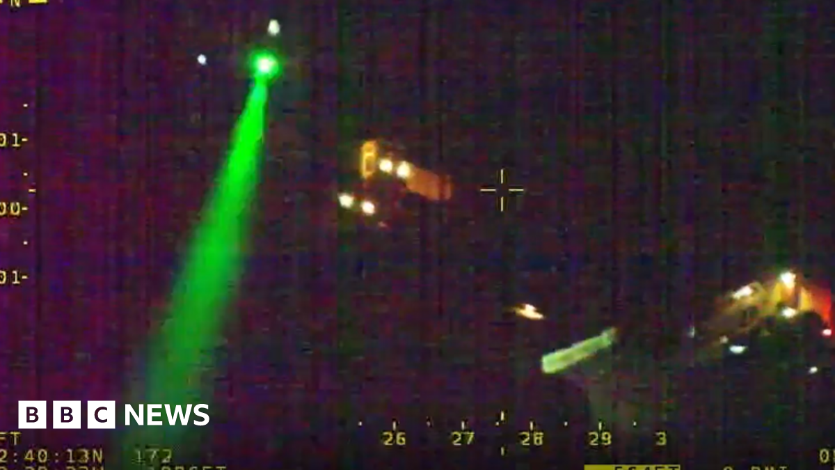 A picture shows darkness, with some lights from houses, and a green laser across the left of the picture. The top right of the picture says West Mercia Police.
