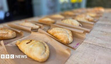Pasties laid out on brown grease-proof paper on a wooden table.