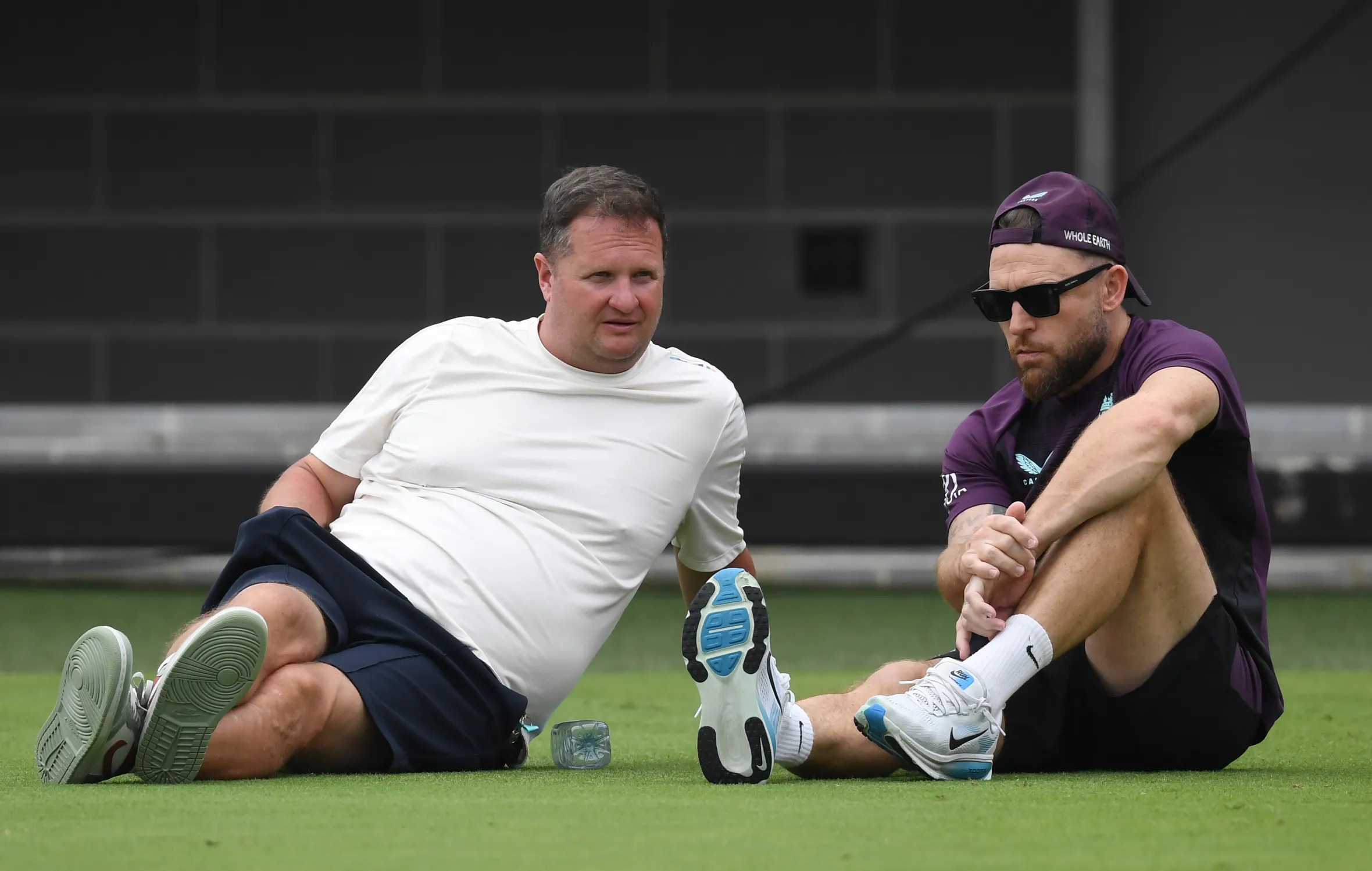 Rob Key and Brendon McCullum sitting on the ground during a training session.