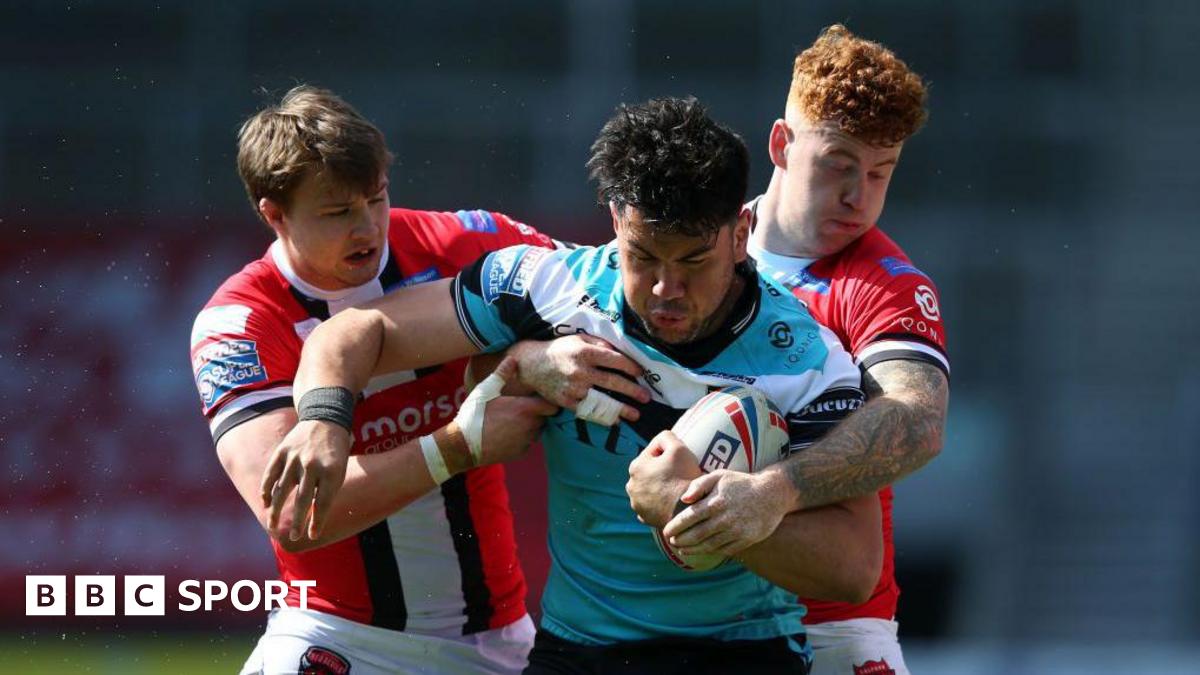 Goole Vikings player Andre Savelio holds onto the ball tenaciously in the blue, black and white of Hull FC as two Salford players try to rip it out of his hands