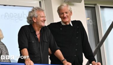 Sir James Dyson and Bruce Craig lean on a balcony at The Rec at a Bath Rugby game together